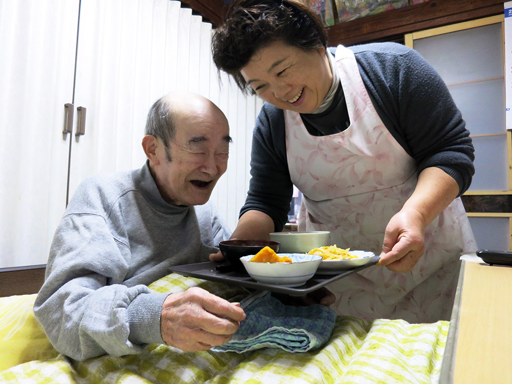 美土里荘訪問介護事業所：ホームヘルパーによる食事介護を受け笑顔の利用者